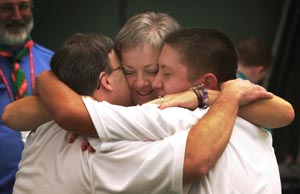 A mom gives a hug to two happy athletes at once